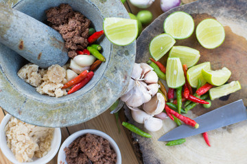 Prepare ingredient inside the stone mortar and grinding for spicy shrimp paste chilli sauce, Thai food.