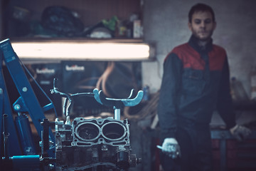 An auto mechanic in special clothes repairs the opposing internal combustion engine.