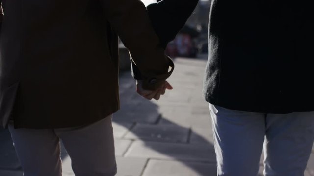 Male couple walking and holding hands, in slow motion