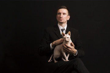 cat sphinx lap of a guy in a suit on a black background