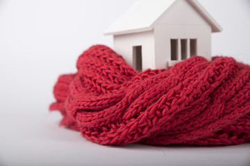 house in winter - heating system concept and cold snowy weather with model of a house wearing a knitted cap