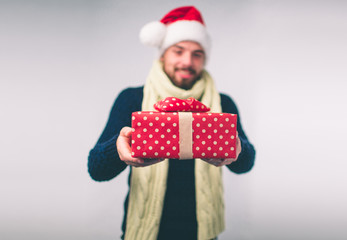 Handsome man in a Christmas hat holding gifts on white background