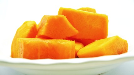 Cut ripe papaya put on blurry white plate - side view, close-up, and selective focus. Deliciously sweet high fibre fruit; rich sources of antioxidant nutrients.