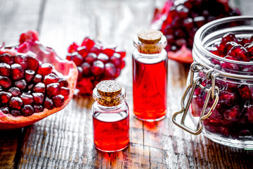 sliced pomegranate and extract in glass on wooden background