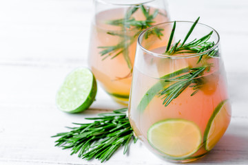 fitness cocktail in glass with lime and rosemary on white table 