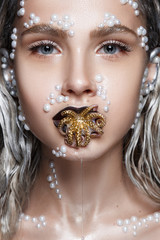 Beautiful woman portrait with art make up, pearl beads on face and gold octopus in mouth. - 188691389