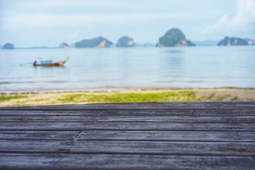 Wooden plank in foreground with blur background of Sea, Mountain and long tail boat in Krabi, Thailand with Montage style and have copy space for text design