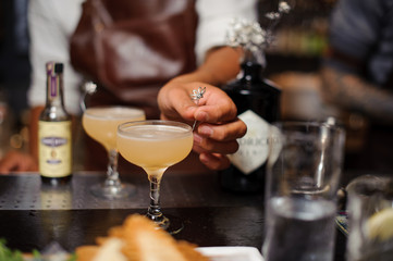 Barman hand decorating a cocktail glass filled with alcoholic drink
