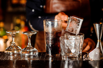 Barman making a cocktail and putting an ice cube into the glass