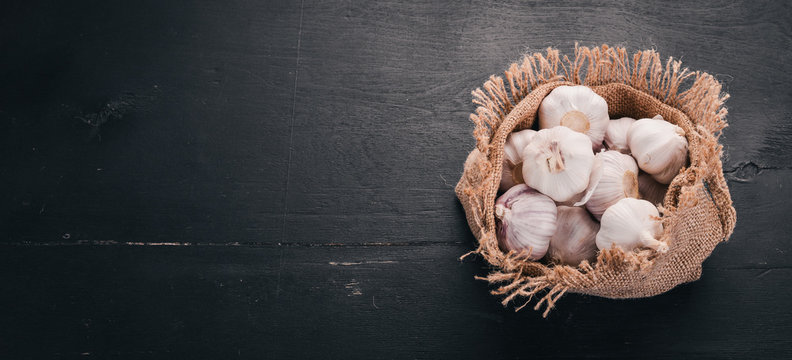 Garlic in a sack of old cloth. Fresh garlic on a wooden background. Top view. Free space for text.