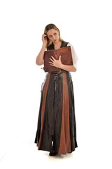  full length portrait of girl wearing brown  fantasy costume, holding a book. standing pose on white studio background. 