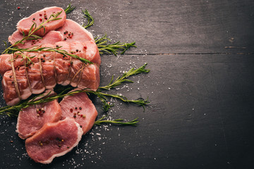 Raw meat Beef fillet with rosemary and spices on a black wooden background. Top view. Free space for text