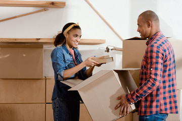 happy african american couple unpacking books in new home