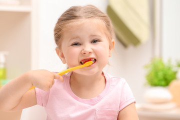 Cute little girl brushing teeth in bathroom