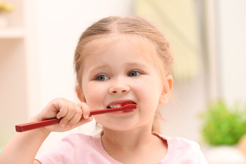 Cute little girl brushing teeth in bathroom