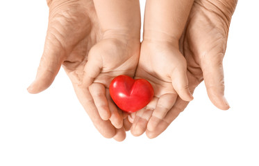 Hands of elderly man and baby with heart on white background