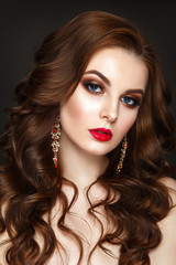 Fototapeta premium Beautiful woman portrait with curly hair, red earrings and evening make up.