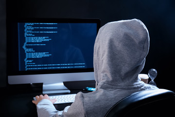 Man wearing hoodie hacking server in dark room