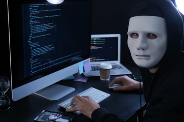 Masked man hacking server in dark room
