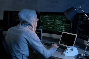 Man wearing hoodie hacking server in dark room