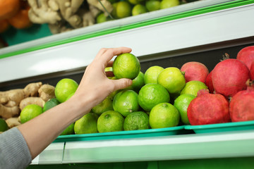 Young woman choosing fresh ripe citrus fruit in supermarket