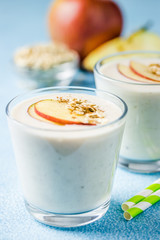 Healthy apple oatmeal cinnamon smoothie in glasses on light blue background. Selective focus, space for text. 