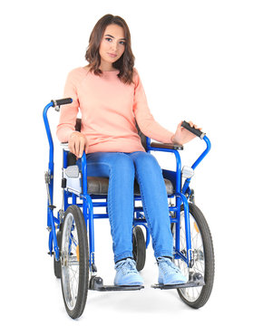 Young woman in blue wheelchair on white background