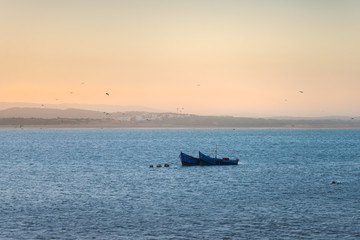 Two blue fishing boats in front of Essaouira city in Morocco.