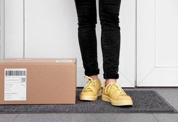 Woman standing near delivered parcel on doormat, closeup