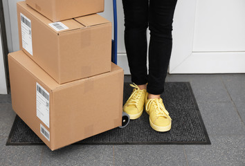 Woman standing near delivered parcels on doormat, closeup