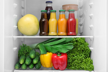 Drinks, vegetables and fruit on refrigerator shelves, closeup