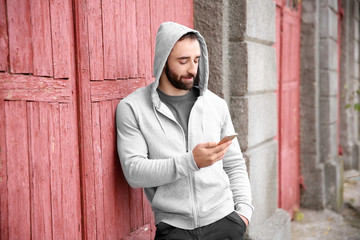 Portrait of young hipster man with phone outdoors