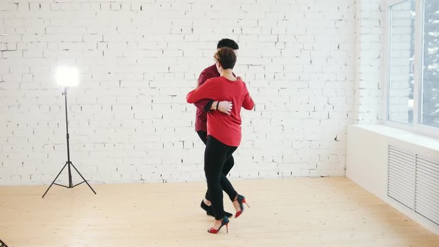 Middle age woman and young man is dancing kizomba in studio, close up