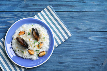 Plate with delicious seafood risotto on wooden table
