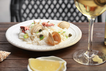 Plate with delicious seafood risotto on wooden table