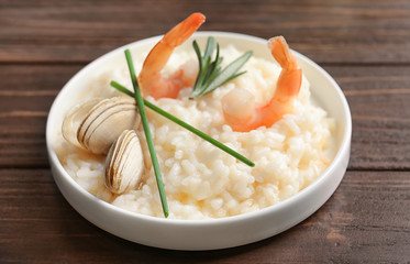 Plate with delicious seafood risotto on wooden table