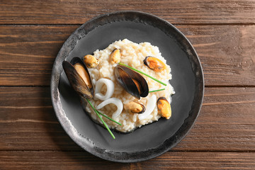 Plate with delicious seafood risotto on wooden table