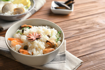 Dish with delicious seafood risotto on wooden table