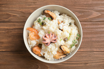 Dish with delicious seafood risotto on wooden table