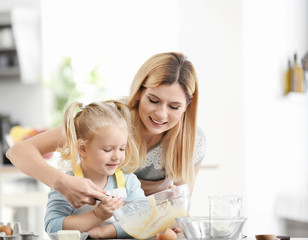 Obraz na płótnie Canvas Mother and daughter preparing dough indoors