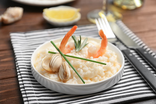 Plate with delicious seafood risotto on wooden table