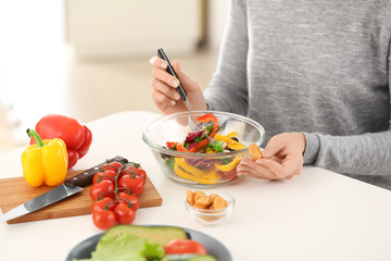 Young woman eating fresh salad at table