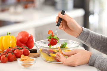Young woman eating fresh salad at table