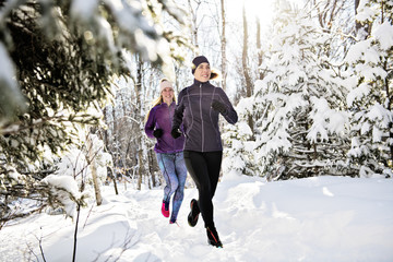 Group of friends enjoying jogging in the snow in winter
