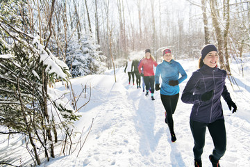 Group of friends enjoying jogging in the snow in winter