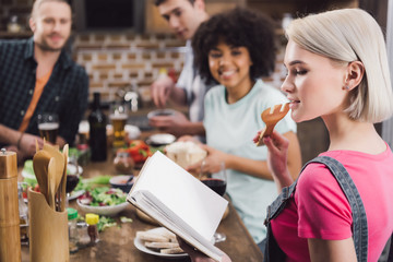 girl holding recipe book and biting wooden spatula