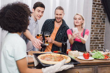 caucasian girl taking photo of african american friends pizza with smartphone