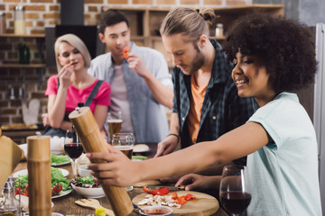 multiethnic friends preparing food together in kitchen