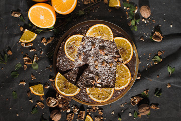 Beautiful and tasty chocolate cake with orange and nut on a dark background