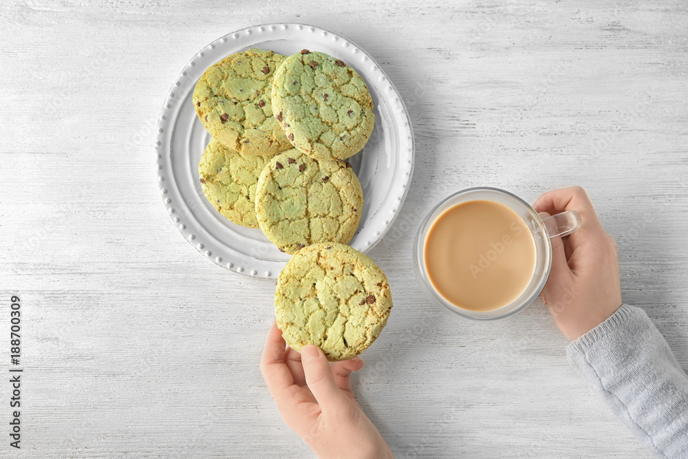 Wall mural Woman with mint oatmeal cookies and cup of coffee at wooden table